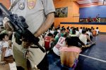 A police officer stands guard over suspected drug users and peddlers in Manila. Photo: UCAN/Vincent Go