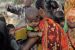 A mother carries her child during a village gathering in Habiganj district of Bangladesh. Photo: UCAN/Stephan Uttom