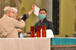 Father Thomas Law demonstrates how to place the face mask on a clean tray covered with tissue when a priest needs to remove it to take Communion at the altar.