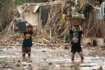 Residents carry their belongings through mud in the Philippines on November 14 after flooding caused by Typhoon Vamco. Photo: CNS / Reuters