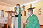 Father Kalisz, left, laying hands on Father Young, right, during the commissioning ceremony on January 11.