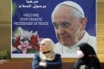 Women stand near a poster of Pope Francis in Baghdad on March 3. Photo:CNS/Reuters