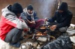 Migrants cook in a temporary shelter near the burned Lipa migrant centre during snowfall and freezing temperatures in Bihac, Bosnia-Herzegovina, on 27 December 2020. Photo: CNS/Reuters