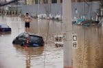 A man stands on a stranded vehicle on a flooded road following heavy rainfall in Zhengzhou, China, on July 22. Photo: CNS /Aly Song, Reuters