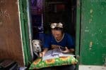 A teenager completes does schoolwork while tending to her family's sidewalk eatery beside their home in Manila, the Philippines, on January 6, as schools were closed during the Covid-19 pandemic. Photo: CNS/Eloisa Lopez, Reuters