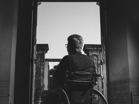 grayscale photography of man sitting on wheelchair