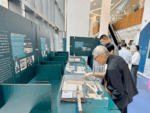 Museum exhibition with glass display cases and informational panels in Chinese and English, visitors examining artifacts together