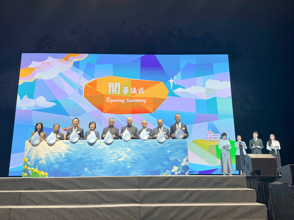 Group of officials standing behind a blue water-themed podium on stage, holding droplet-shaped props at an Opening Ceremony.