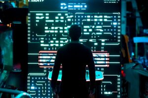 Person seen from behind facing a large glowing digital screen with circuit-like neon patterns in a dark arcade or lab setting.