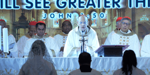 Bride and groom stand before an altar as a bishop and priests celebrate Mass from behind the couple